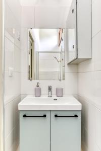 un bagno bianco con lavandino e specchio di Appartement rez-de-chaussée Plage du Grazel a Gruissan