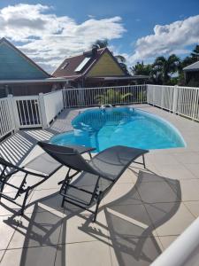 a patio with two chairs and a swimming pool at Résidence des Pikaniers in Anse-Bertrand