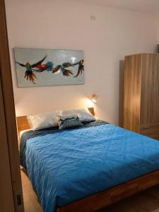 a bedroom with a bed with blue sheets and a painting on the wall at Mare&Relax in Mazara del Vallo