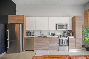a kitchen with white cabinets and a stainless steel refrigerator at Stunning Downtown Apartment with Pool, Laundry, Parking in Dallas