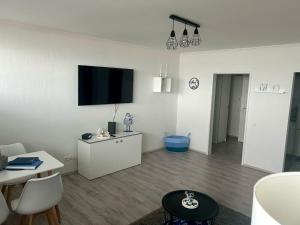 a white living room with a flat screen tv on the wall at Ferienwohnung Moin in Bremerhaven