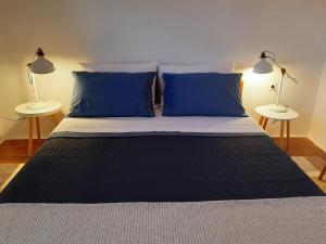 a large bed with blue pillows and two lamps at Apartment ZenPunta in Pučišća