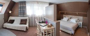 a hotel room with two beds and a table and a desk at Logis Hotel Du Casino Restaurant Le Mathelia in Vierville-sur-Mer