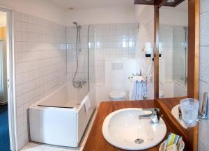 a bathroom with a sink and a shower and a tub at Logis Hotel Du Casino Restaurant Le Mathelia in Vierville-sur-Mer