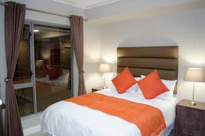 1 dormitorio con 1 cama grande con almohadas de color naranja en Mayfair Luxury Apartments, en Ciudad del Cabo