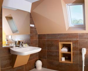 a bathroom with a sink and a window at Logis Hotel Du Casino Restaurant Le Mathelia in Vierville-sur-Mer