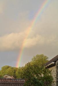 um arco-íris no céu sobre uma casa em Gite de Charme em Villeneuve-sur-Auvers