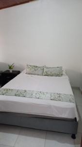 a bedroom with a bed with white sheets and pillows at Casa Villetana in Villeta