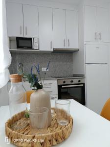 a kitchen with white cabinets and a table with a vase at As Mimosas d'Cross in Redondela +44 photos