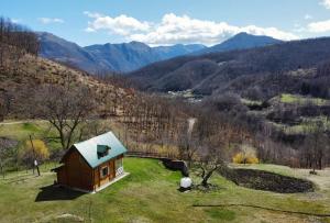 a small cabin on a hill with mountains in the background at Red Forest house in Andrijevica