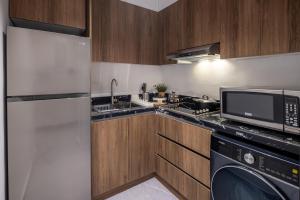 a kitchen with a refrigerator and a microwave at Delmar Luxury 3BR Apartment 4 in Jeddah