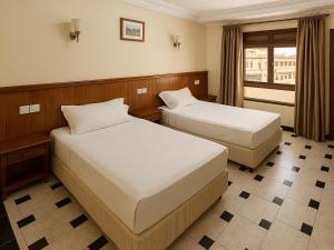 een hotelkamer met twee bedden en een raam bij Hôtel Nexus Budget in Al Hoceïma