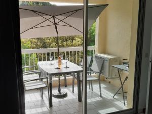 einen Tisch mit Weingläsern und einem Sonnenschirm auf dem Balkon in der Unterkunft Home cavalaire in Cavalaire-sur-Mer