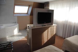 ein Badezimmer mit einem TV auf einem Stand mit einer Badewanne in der Unterkunft Logis Hotel Du Casino Restaurant Le Mathelia in Vierville-sur-Mer