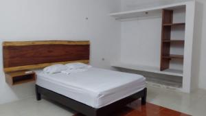 a bedroom with a white bed with a wooden headboard at Casa Valdez in Valladolid