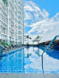 a swimming pool at a resort with chairs and a building at Jessa Rios Coast Staycation in Manila