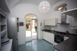 a kitchen with white cabinets and a chandelier at Villa Mascia in Anacapri
