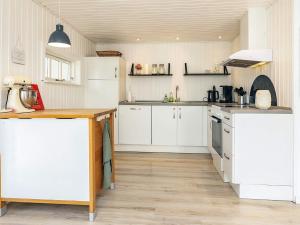 a kitchen with white cabinets and a wooden floor at Cozy Summer House Near Ore Strand in Vordingborg +33 photos