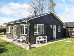 a small black shed with two chairs in a yard at Cozy Summer House Near Ore Strand in Vordingborg