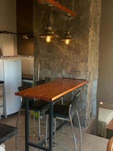 a dining room table with chairs and a stone wall at Cabaña Casa Flor Bru in Villa Yacanto +2 photos