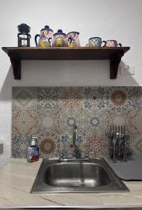 a kitchen sink with a shelf with dishes on it at Casa Flamboyán in Santa Bárbara