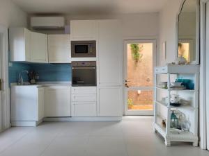 a white kitchen with white cabinets and a window at Casa Tiemme Vista Mare in Costa Paradiso