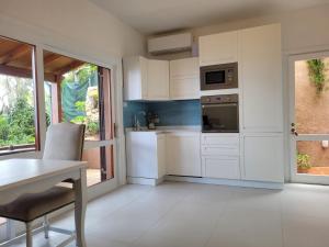 a kitchen with white cabinets and a table and a window at Casa Tiemme Vista Mare in Costa Paradiso +38 photos
