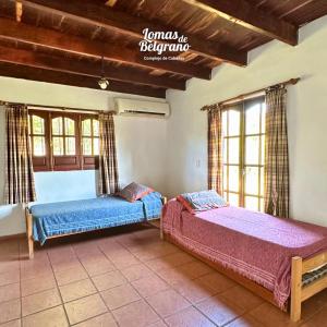 2 Betten in einem Zimmer mit Fenstern in der Unterkunft Lomas de Belgrano Oficial cabaña 1 in Villa General Belgrano