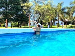 Eine Frau mit einem Hut steht im Pool in der Unterkunft Lomas de Belgrano Oficial cabaña 1 in Villa General Belgrano