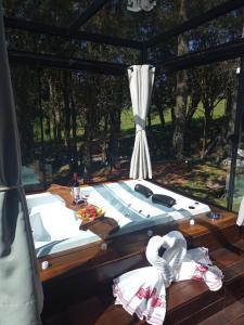 a bed on a deck with a large window at Choupanas Chalé in São José dos Pinhais