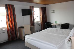 a hotel room with a white bed and a desk at Martinshof in Zuchwil