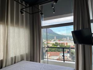 a bedroom with a bed and a window with a television at Skyloft in Governador Valadares