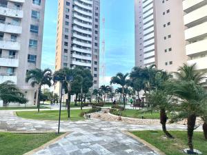 a park with palm trees and tall buildings at Condomínio Natture Clube in Natal