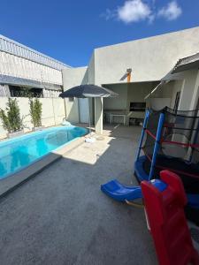 una piscina con sillas y una sombrilla junto a una piscina en Casa de 2 dormitórios com piscina, en Pelotas