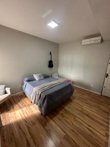 a bedroom with a bed and a wooden floor at Casa de 2 dormitórios com piscina in Pelotas +16 photos