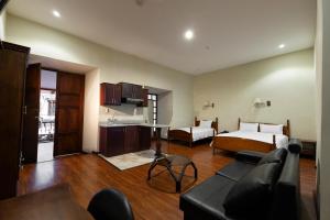 a living room with a bed and a couch and a kitchen at Hotel & Suites El Quijote in Cuenca