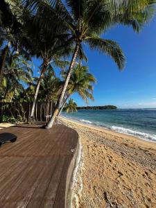 a wooden boardwalk on a beach with palm trees at Charish del Mar in Baganga +5 photos