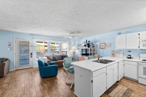 eine Küche mit weißen Schränken und ein Wohnzimmer in der Unterkunft Peachtree Place Ii C202 in Panama City Beach + 16 Fotos