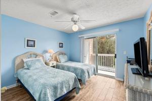 1 Schlafzimmer mit 2 Betten, einem TV und einem Balkon in der Unterkunft Peachtree Place Ii C202 in Panama City Beach