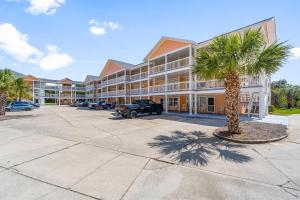 ein großes Gebäude mit einer Palme auf einem Parkplatz in der Unterkunft Peachtree Place Ii C202 in Panama City Beach