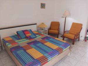 a bedroom with a colorful bed and two chairs at Studio Marina de Saint-François in Saint-François