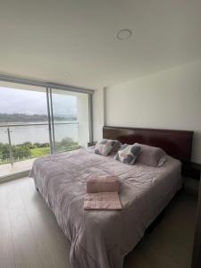a bedroom with a large bed with a large window at Apartamento con vista al lago Sochagota in Paipa