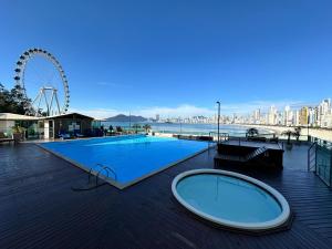 a large swimming pool with a ferris wheel in the background at Flat - Frente Mar, Roda Gigante e Estrada da Rainha in Balneário Camboriú