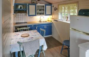 a small kitchen with blue cabinets and a table with chairs at Holiday Home Ombo Iii in Omböy