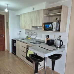a kitchen with a counter with stools and a stove at Departamento Central Osorno 2 in Osorno