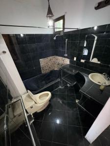a black tiled bathroom with a toilet and a sink at Hostal Colonial Independiente in Mixco +24 photos
