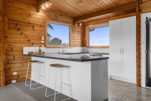 a kitchen with white cabinets and a counter with stools at The Wee Glen - Peaceful Country Retreat in Bennetts