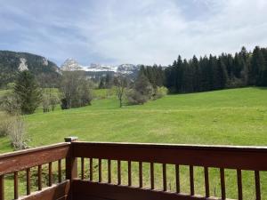 a deck with a view of a green field and mountains at Appartement 3 Pièces au Pied des Pistes, 6 Couchages - FR-1-761-47 in Corrençon-en-Vercors