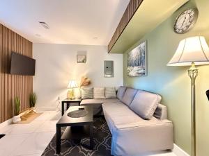 a living room with a couch and a clock on the wall at Brand New 2 Bedroom Suite in Langley Twp - Play Area, Patio & Mini Golf in Aldergrove