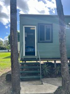 a green tiny house with a porch and two trees at gundy pub & caravan park in Gundiah +22 photos